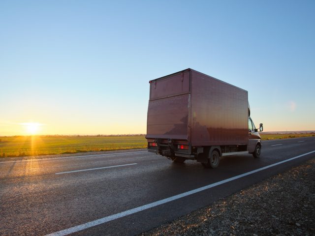 Cargo truck driving on highway hauling goods in evening. Delivery transportation and logistics